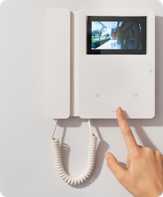 Individual pressing a video doorbell on a wall, highlighting advanced intercom services for enhanced communication.