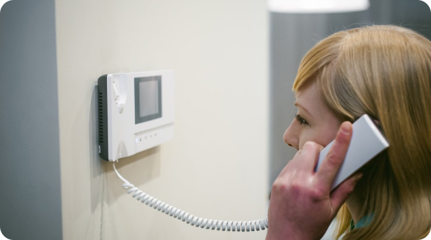 A woman on a call with one phone, holding another phone, symbolizing intercom service operations.